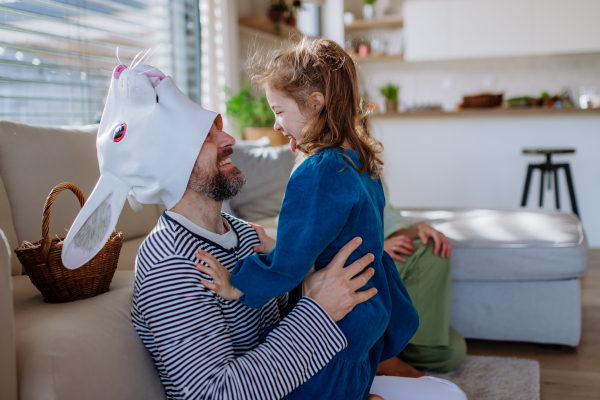 Little girl having fun with her father, who is wearing Easter rabbit costume.