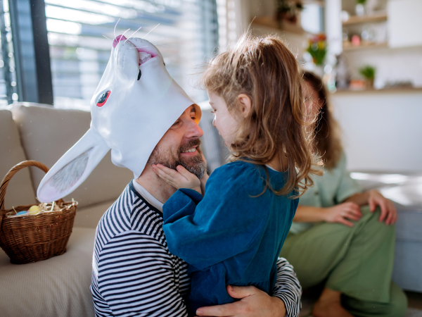 Little children having fun with her dad in Easter rabbit mask, celebrating Easter.