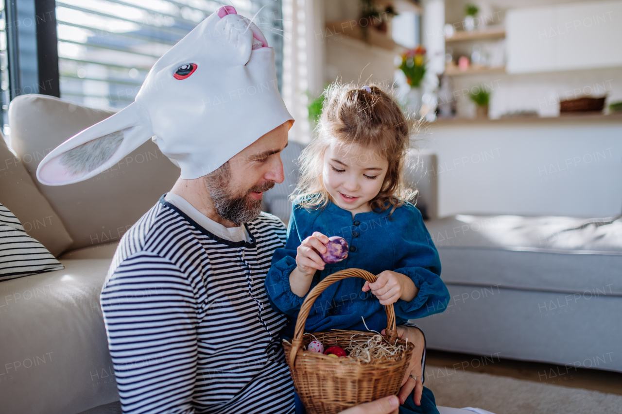 Little girl with bunny ears holding basket and showing her father easter eggs which she found.