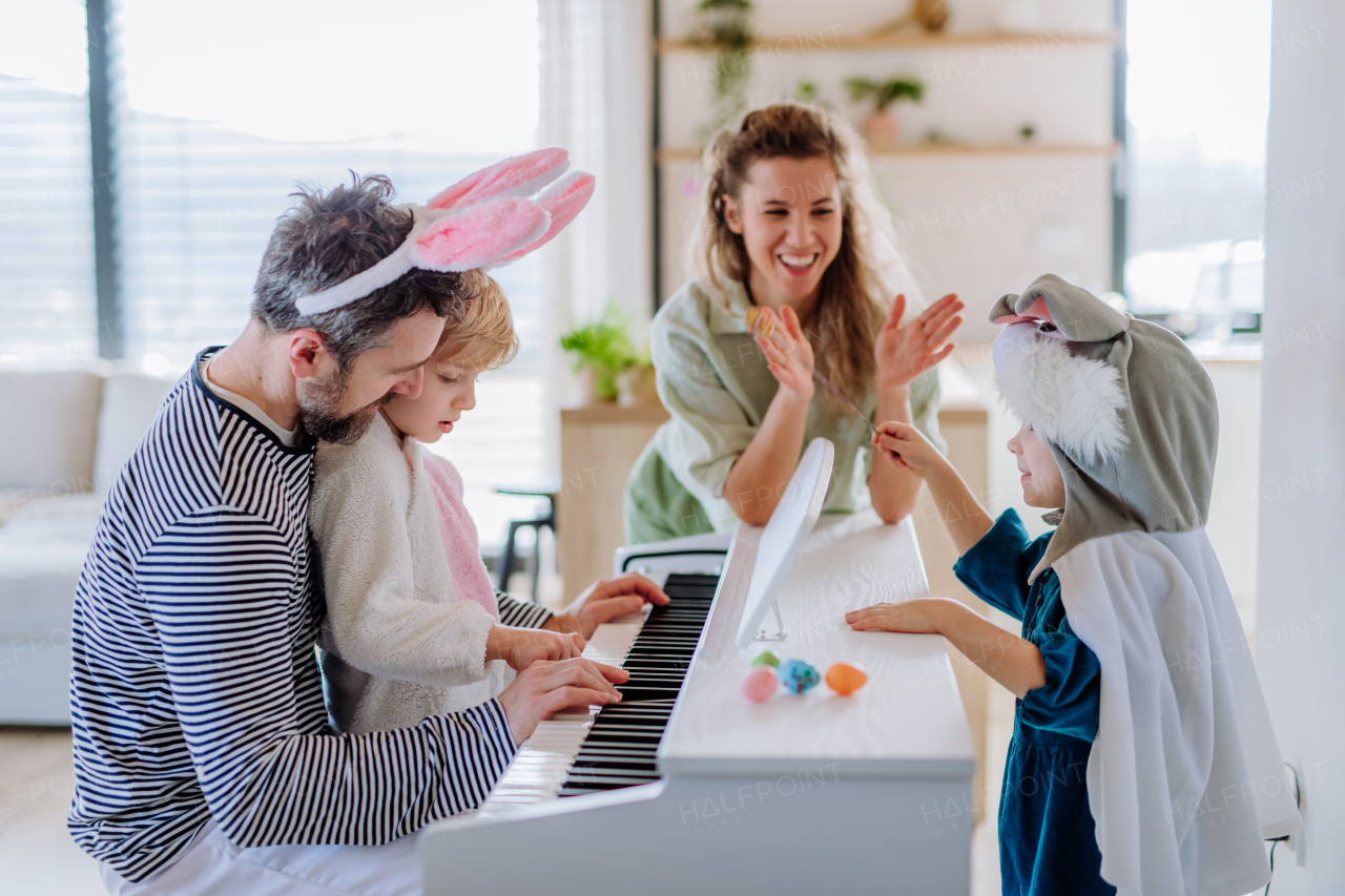 Happy family with small children in easter costumes playing on the piano.