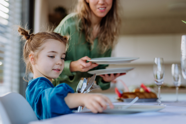 Close-up of mother with her daughter setting the table, celebrating Easter.