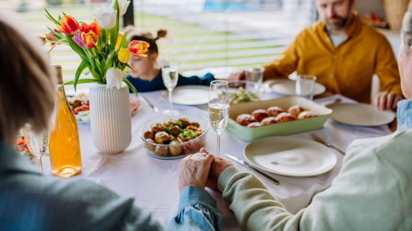 Close-up of family holding hands, praying before Easter dinner.