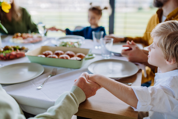 Close-up of family holding hands, praying before Easter dinner.