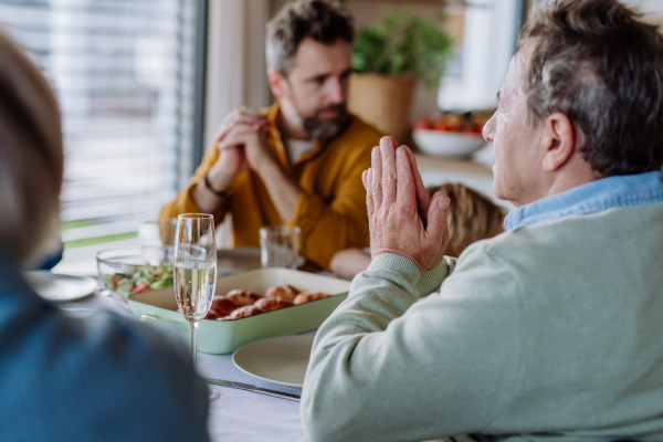 Close-up of family praying before Easter dinner.