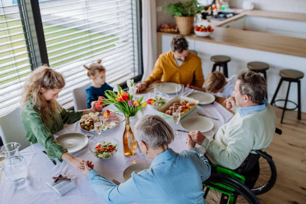 Close-up of family holding hands, praying before Easter dinner.