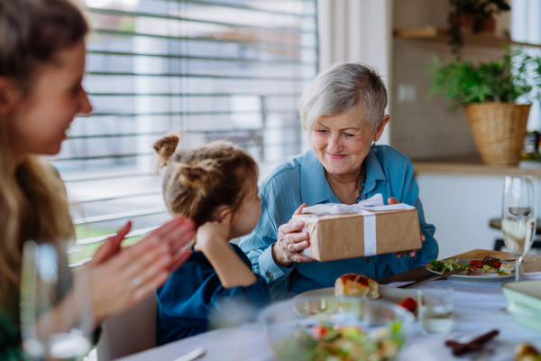 Grandmother giving gift to her granddaughter during an Easter dinner.