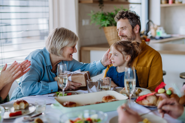 Grandmother giving gift to her granddaughter during an Easter dinner.