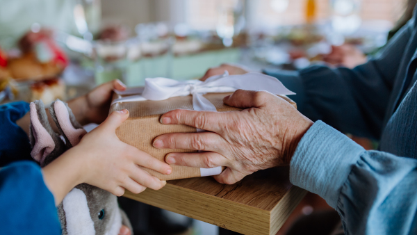 Grandmother giving gift to her granddaughter during an Easter dinner, close-up.