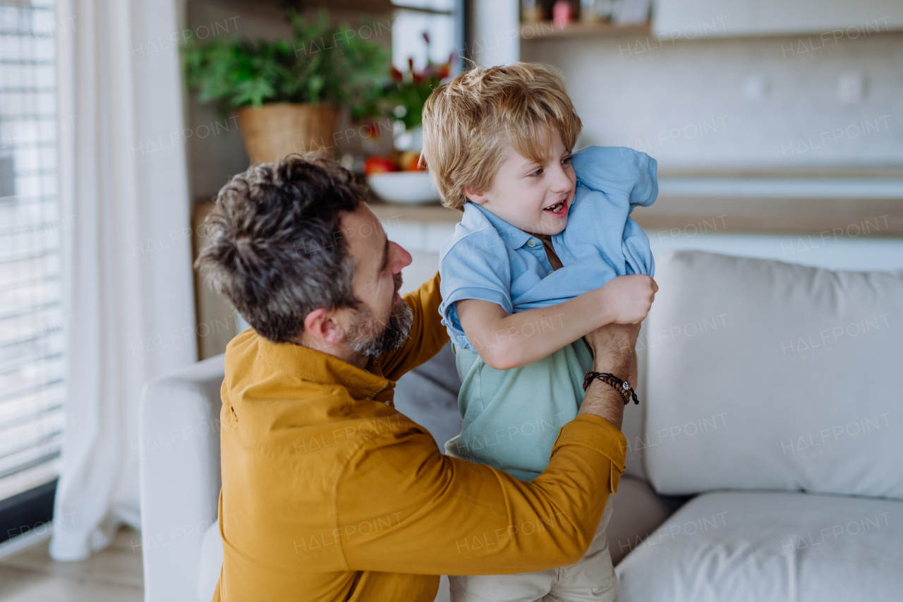 Happy father changing t-shirt to his little son.