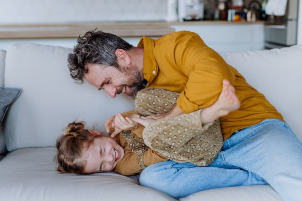 Father tickling his little daughter, having fun together.