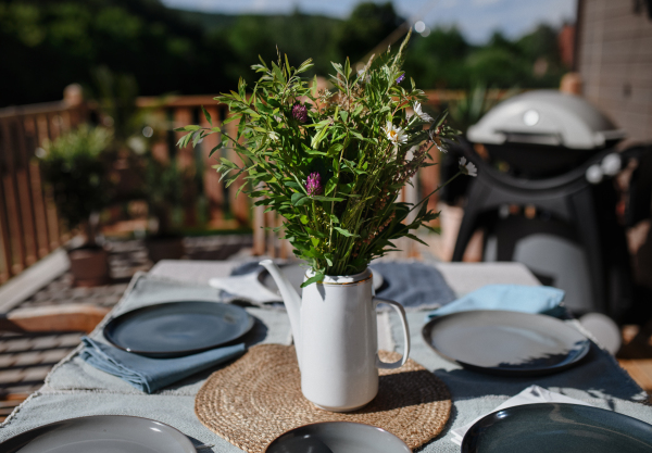 A dining table with bouquet set for dinner on the terrace with grill in summer, garden party. concept.