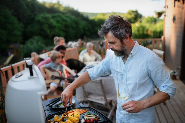 Mature man grilling food at family bbq party.