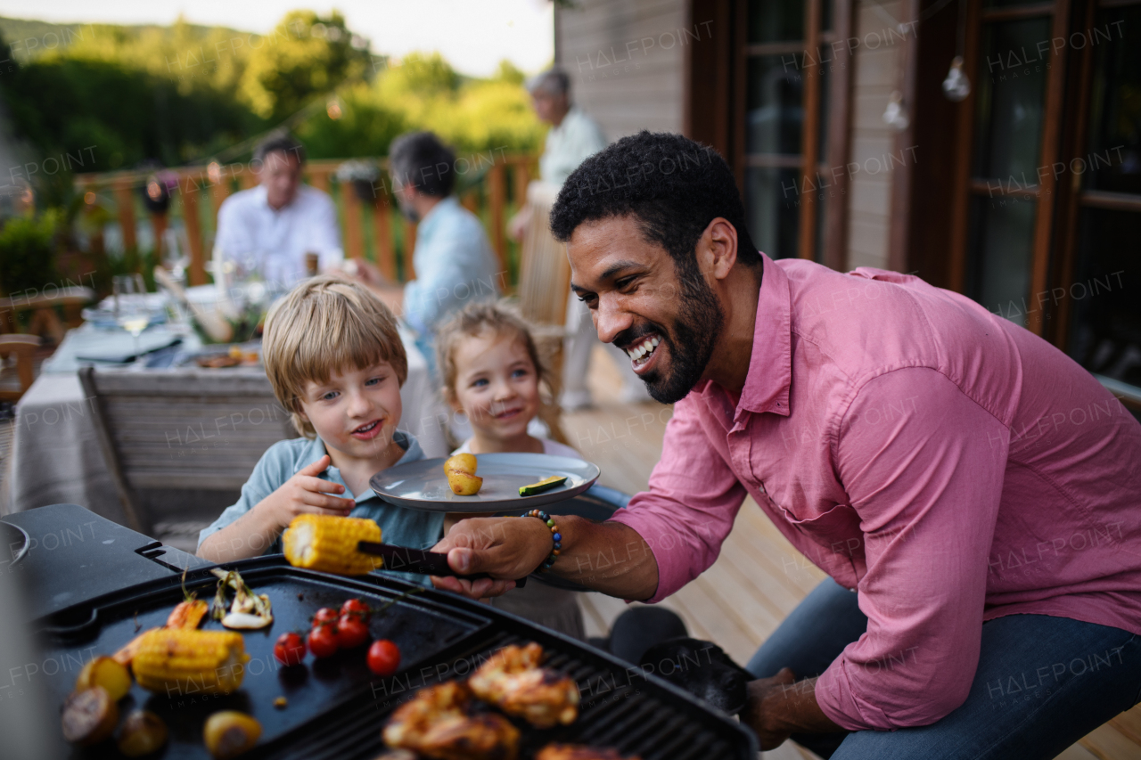 Multi generation family having party outside in the backyard on a patio.