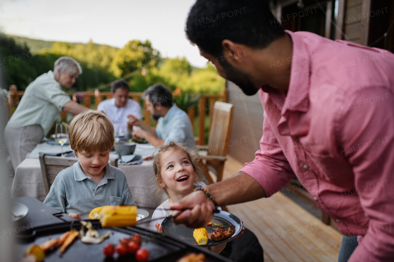 Multi generation family having party outside in the backyard on a patio.