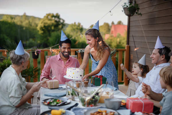 A multi generation family celebratiing birthday and have garden party outside in the backyard on patio.