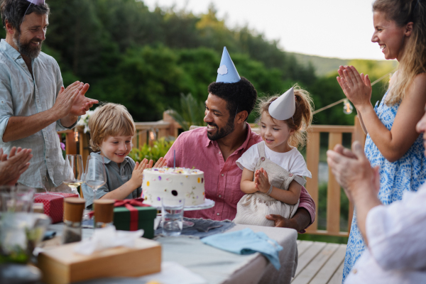 A multi generation family celebratiing birthday and have garden party outside in the backyard on patio.