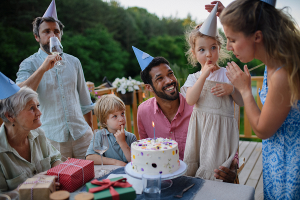 A multi generation family celebratiing birthday and have garden party outside in the backyard on patio.