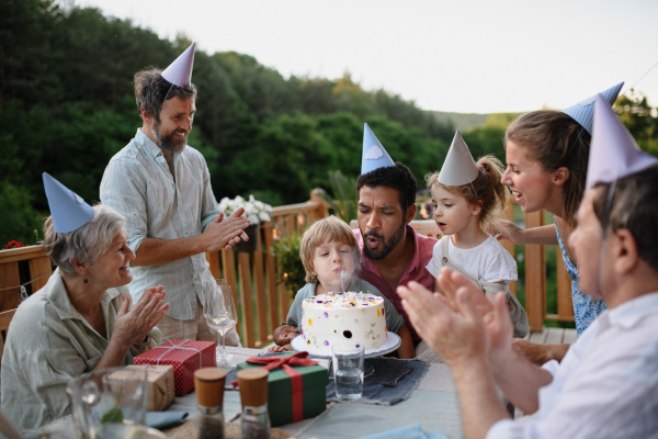 A multi generation family celebratiing birthday and have garden party outside in the backyard on patio.