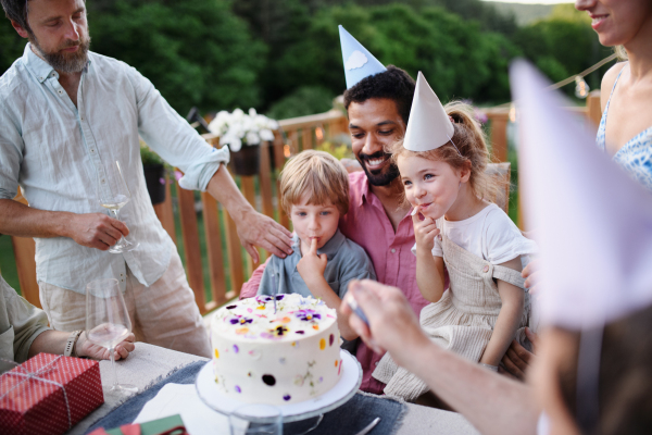 A multi generation family celebratiing birthday and have garden party outside in the backyard on patio.