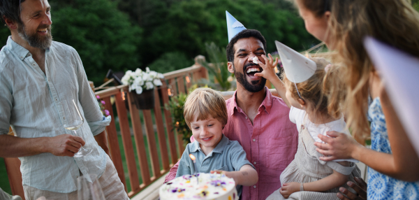 A multi generation family celebratiing birthday and have garden party outside in the backyard on patio.