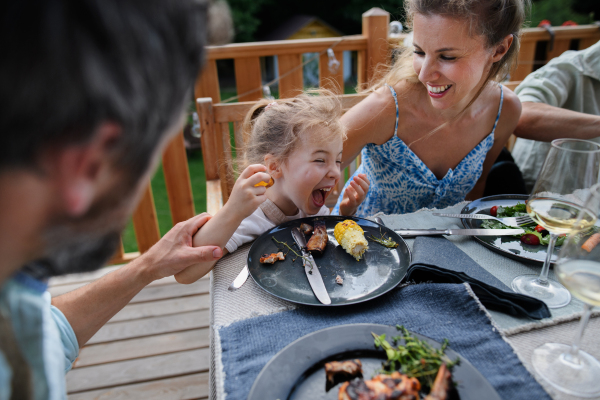 A family eating at barbecue party dinner on a patio, lhaving fun and enjoying it.