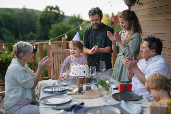 A multi generation family celebratiing birthday and have garden party outside in the backyard on patio.