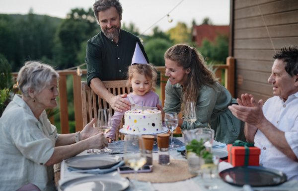 A multi generation family celebratiing birthday and have garden party outside in the backyard on patio.