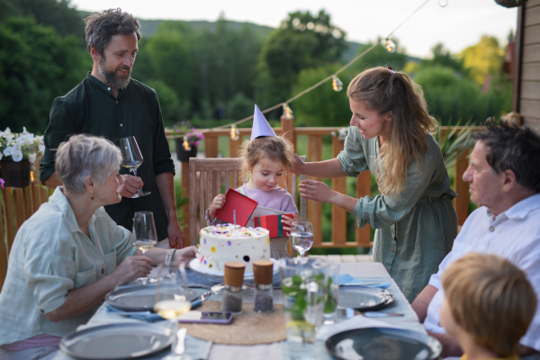 A multi generation family celebratiing birthday and have garden party outside in the backyard on patio.