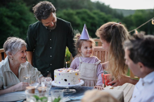 A multi generation family celebratiing birthday and have garden party outside in the backyard on patio.