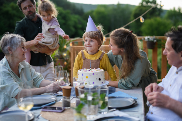 A multi generation family celebratiing birthday and have garden party outside in the backyard on patio.