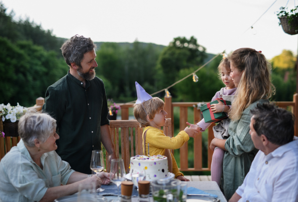 A multi generation family celebratiing birthday and have garden party outside in the backyard on patio.