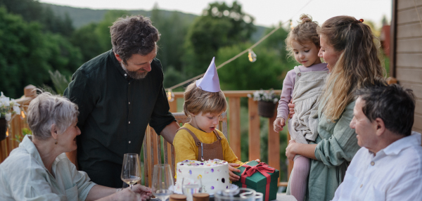 A multi generation family celebratiing birthday and have garden party outside in the backyard on patio.