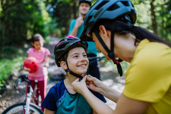 A young family with little children preapring for bike ride, standing with bicycles in nature.