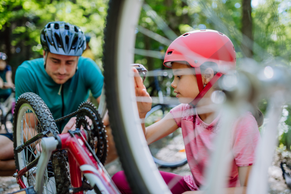 A young family with little children preapring for bike ride, standing with bicycles in nature.