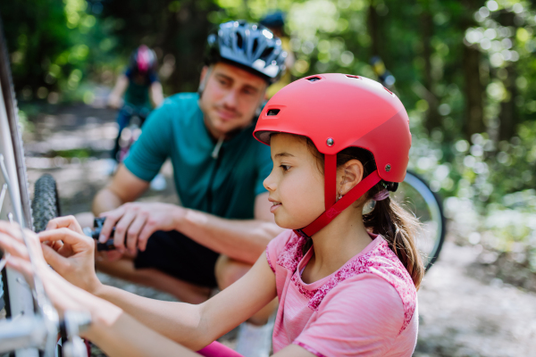 Father chcecking bicycle to her daughter during family trip in a nature.