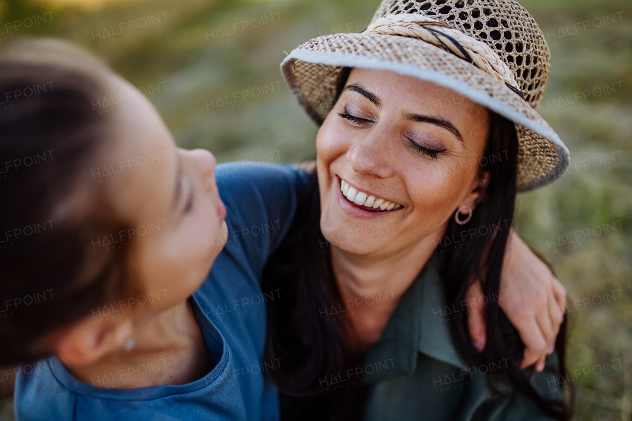 Happy, affectionate mother and daughter hugging during sunset.