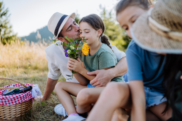 Happy father and his daughter hugging together, celebrating birthday during family picnic in the nature.