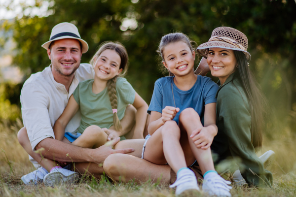 Happy family sitting on medow, resting after hiking in nature.