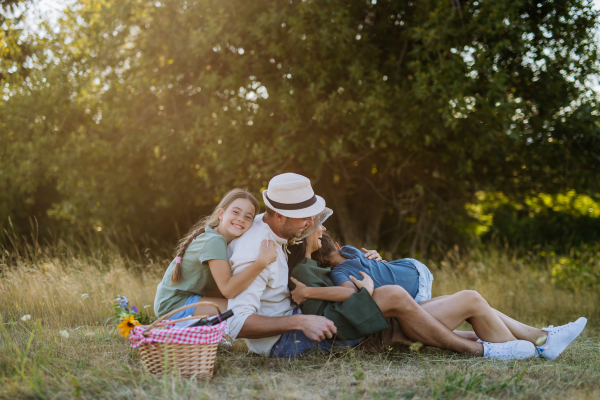 Happy family sitting on medow, resting after hiking in nature.