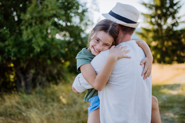 A father hugging his daughter in summer in nature. Father's day concept.