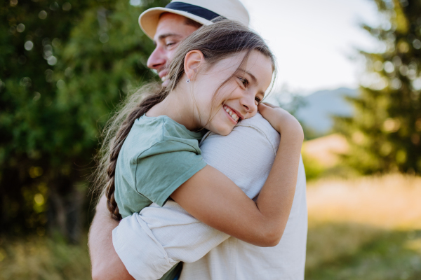 A father hugging his daughter in summer in nature. Father's day concept.