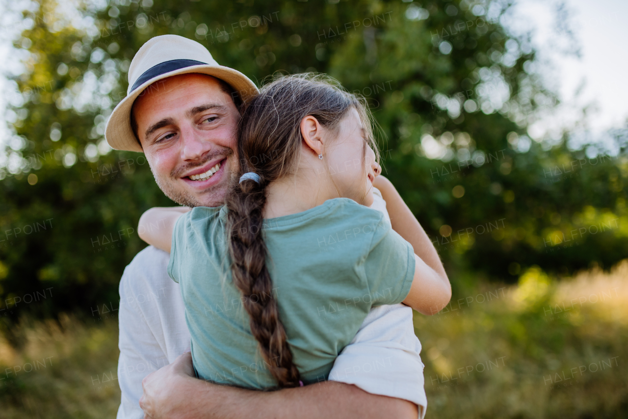 A father hugging his daughter in summer in nature. Father's day concept.