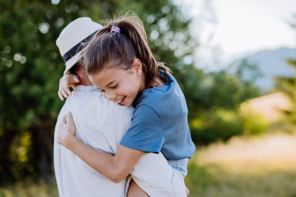 A father hugging his daughter in summer in nature. Father's day concept.