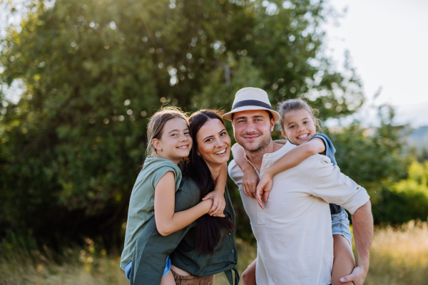 A happy family with two small daughters standing outdoors in summer nature.