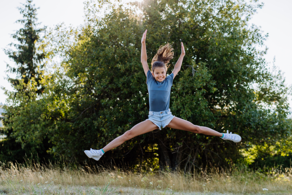 Young excited girl jumping in the forest.