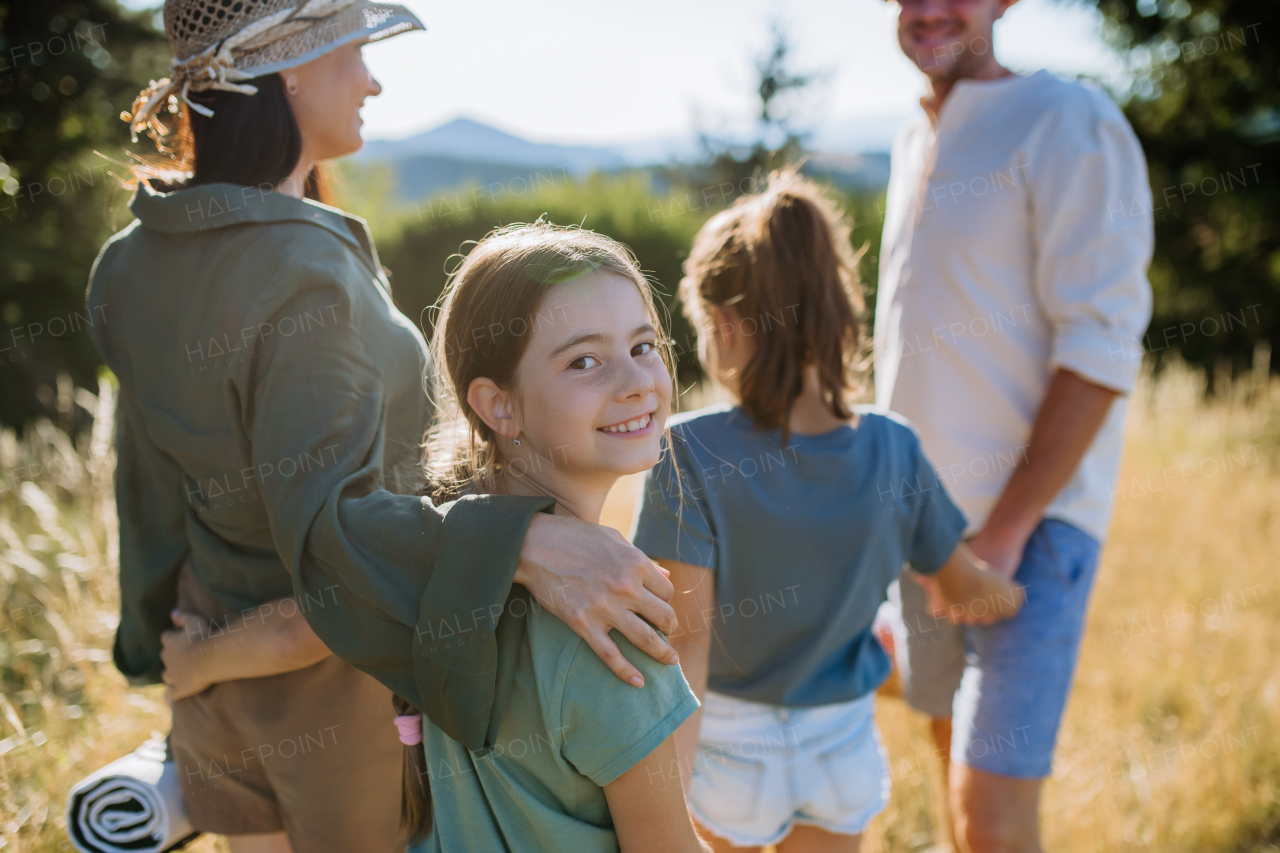 A happy young parents with daughters walking for picnic in nature in summer day.