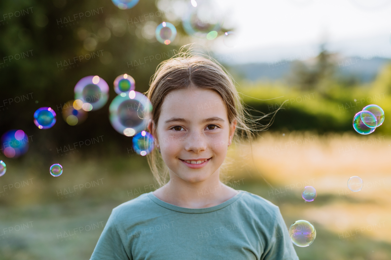 Portrait of a beautiful little girl smiling in nature, with the bubbles in the background.