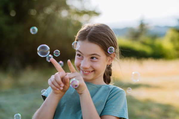 Portrait of a beautiful little girl smiling in nature, with the bubbles in the background.