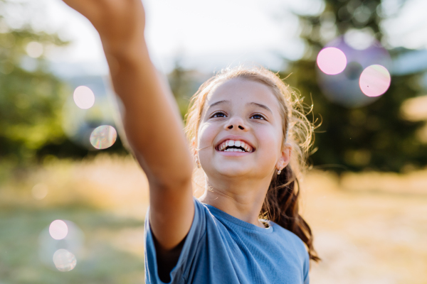 Portrait of a beautiful little girl smiling in nature, with the bubbles in the background.