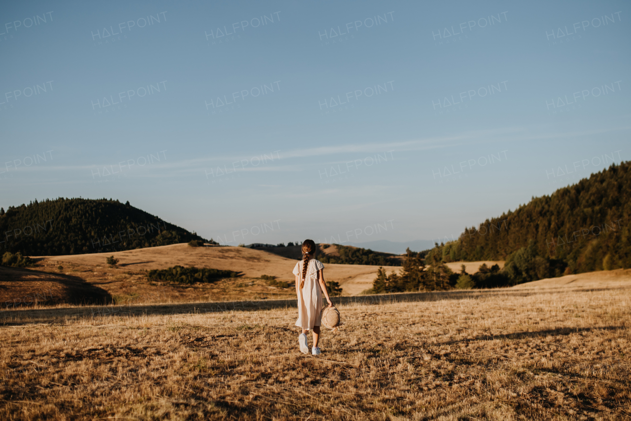 Rear view of a little girl feeling free in summer in nature.